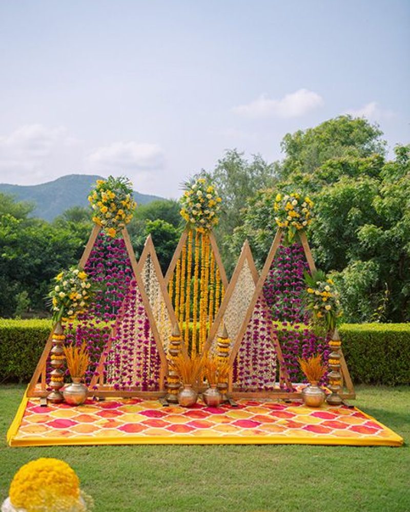 Vibrant Haldi Stage_ Triangular Arches with Bright Floral Garlands